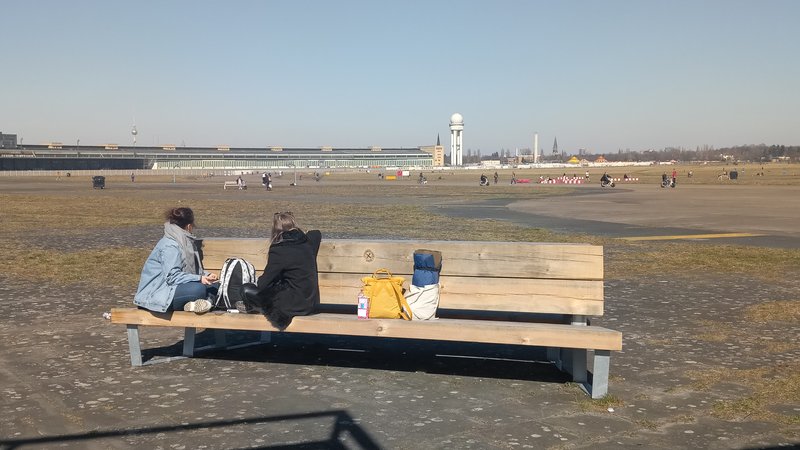 Sitzbank aus Holz mit 2 Personen auf dem Tempelhofer Feld
