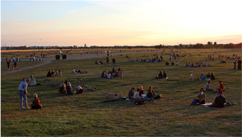Kleingruppen auf den Wiesen des Tempelhofer Feldes im Sonnenuntergang